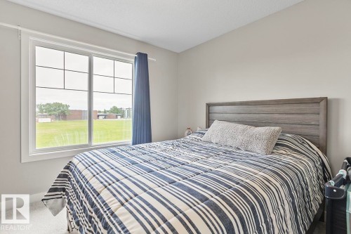 Room featuring a large window with white trim, offering views of a green field - 22 3025 151 Avenue, Edmonton, AB 
