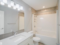 Full bathroom featuring a white vanity with an integrated sink, polished chrome faucet, and under-counter cabinetry - 