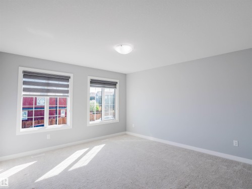 Carpeted room featuring two windows with blinds, light gray walls, and white baseboards - 2526 Wonnacott Loop, Edmonton, AB 