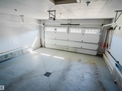 Spacious garage featuring a white overhead door with upper window panes, an automatic opener, a concrete floor with a central drain, and overhead lighting - 