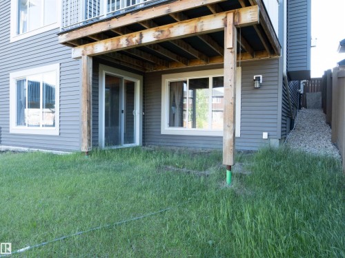 Lower-level patio area featuring a wooden deck structure, sliding glass door access, and a large picture window - 2526 Wonnacott Loop, Edmonton, AB 