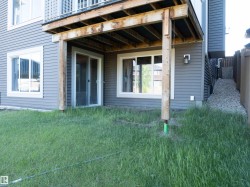 Lower-level patio area featuring a wooden deck structure, sliding glass door access, and a large picture window - 
