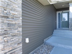 Exterior entry featuring horizontal siding and stacked stone facade - 
