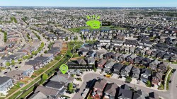 Aerial perspective of a dense residential development featuring a variety of single-family homes and townhomes, green spaces, and a prominent pond - 