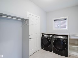 Dedicated laundry area featuring a countertop surface, integrated shelving, and light wood-finish flooring - 