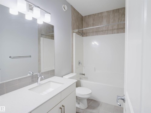 Modern bathroom featuring a white vanity with integrated sink, chrome faucet, and overhead bar lighting - 2526 Wonnacott Loop, Edmonton, AB 