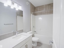 Modern bathroom featuring a white vanity with integrated sink, chrome faucet, and overhead bar lighting - 