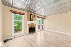Spacious room featuring light wood-finish flooring, a decorative metal tile ceiling, and neutral wall tones - 
