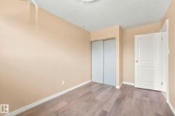 Interior room featuring wood-finish flooring, light beige walls, and white baseboards - 