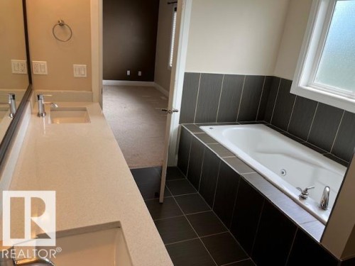 Double vanity with integrated rectangular sinks and polished chrome single-handle faucets, set on a light-toned countertop - 805 Hodgins Road, Edmonton, AB 