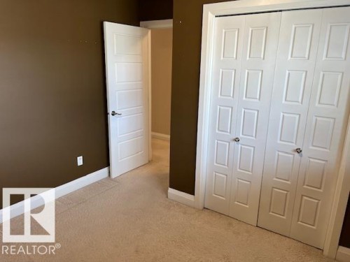 Room featuring plush carpet flooring, bi-fold closet doors, a five-panel interior door, and contrasting wall colors - 805 Hodgins Road, Edmonton, AB 