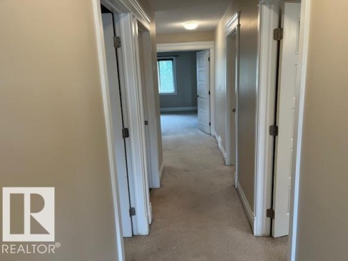Interior hallway featuring neutral wall paint, white trim, and carpet flooring - 805 Hodgins Road, Edmonton, AB 