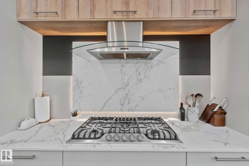 Integrated gas cooktop on a white stone countertop with natural wood-finish upper cabinetry - 4509 Wingfield Bay Bay, Edmonton, AB 