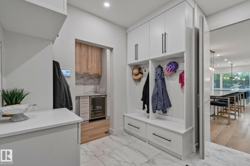 Custom built-in mudroom cabinetry with a bench and storage drawers, complemented by marble-finish tile flooring - 4509 Wingfield Bay Bay, Edmonton, AB 