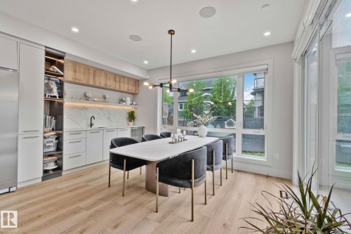 Open-concept dining area featuring light wood-finish flooring and extensive natural light - 4509 Wingfield Bay Bay, Edmonton, AB 