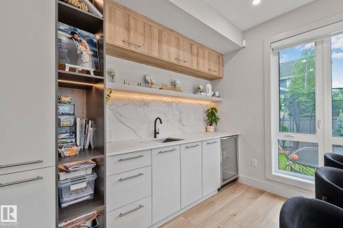 Integrated wet bar featuring a black faucet, undermount sink, and under-counter beverage refrigerator - 4509 Wingfield Bay Bay, Edmonton, AB 