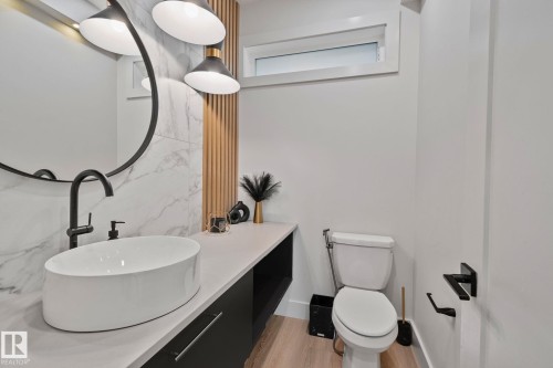 Modern powder room featuring a vessel sink, matte black hardware, and a wood-slatted accent wall - 4509 Wingfield Bay Bay, Edmonton, AB 