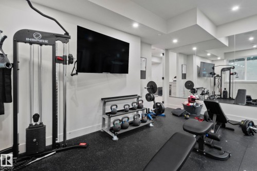 Dedicated fitness room featuring black rubber flooring, recessed lighting, a wall-mounted display, and full-wall mirrors - 4509 Wingfield Bay Bay, Edmonton, AB 