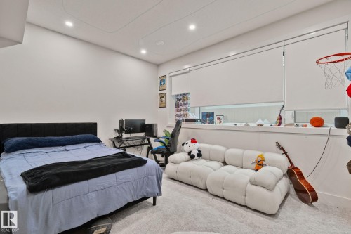 Spacious room featuring light gray carpet flooring, recessed ceiling lighting, and a large window with roller shades - 4509 Wingfield Bay Bay, Edmonton, AB 