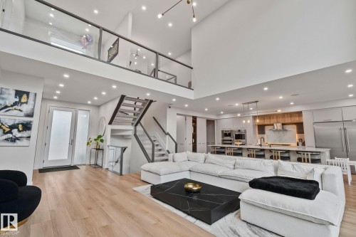 Vaulted ceilings enhance this open-concept living space, featuring wood-finish flooring and recessed lighting - 4509 Wingfield Bay Bay, Edmonton, AB 