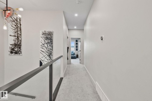Hallway featuring recessed lighting, a modern chandelier, and a glass-paneled railing - 4509 Wingfield Bay Bay, Edmonton, AB 