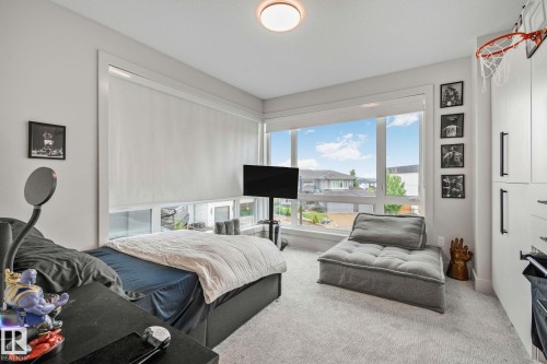 Room featuring large windows with roller shades, white built-in cabinetry with black hardware, and light-colored carpet flooring - 4509 Wingfield Bay Bay, Edmonton, AB 