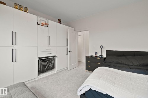 Built-in white cabinetry with black hardware, integrated drawers, and pull-out hampers - 4509 Wingfield Bay Bay, Edmonton, AB 