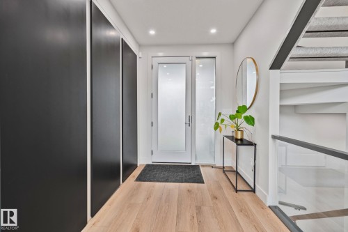 Entryway featuring wood-finish flooring, recessed lighting, and a white entry door with frosted glass panels - 4509 Wingfield Bay Bay, Edmonton, AB 