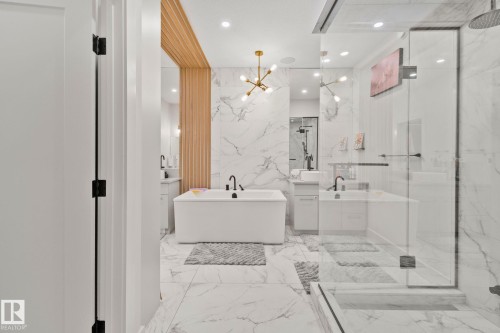 Spacious bathroom featuring a freestanding tub, glass-enclosed shower, dual vanities with undermount sinks, and marble-look tile flooring and walls - 4509 Wingfield Bay Bay, Edmonton, AB 