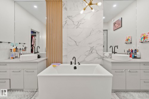 Sleek bathroom featuring a deep soaking tub, dual floating vanities with vessel sinks, and matte black fixtures - 4509 Wingfield Bay Bay, Edmonton, AB 