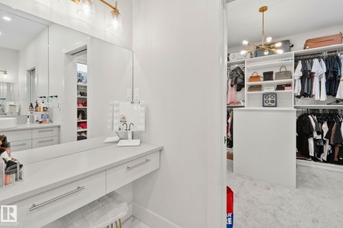 Built-in vanity with a full-width mirror and a modern brass light fixture - 4509 Wingfield Bay Bay, Edmonton, AB 