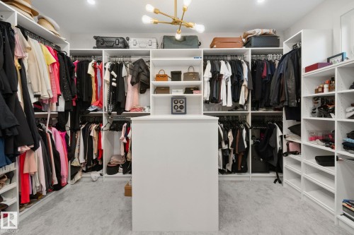 Custom closet system featuring extensive shelving, multiple hanging rods, a central island, and recessed lighting - 4509 Wingfield Bay Bay, Edmonton, AB 