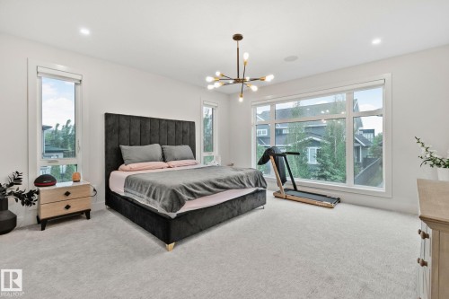 Spacious room featuring multiple windows, light-colored carpeting, recessed lighting, and a contemporary chandelier - 4509 Wingfield Bay Bay, Edmonton, AB 