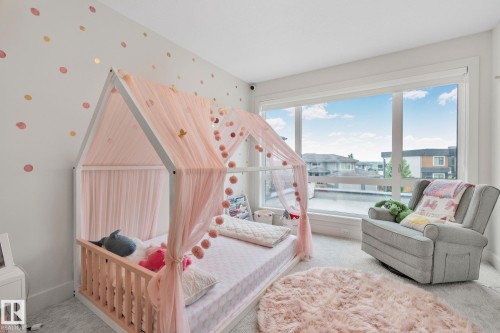 Bright room featuring a large picture window, light gray carpeting, and white walls with decorative polka dots - 4509 Wingfield Bay Bay, Edmonton, AB 