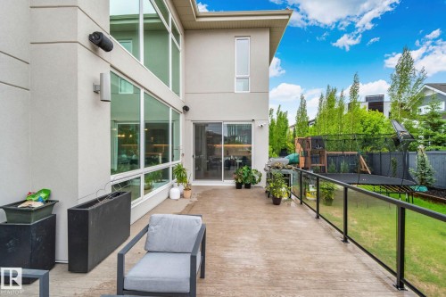 Spacious outdoor deck featuring wood-finish flooring, a contemporary glass railing, and direct access to the interior through a sliding glass door - 4509 Wingfield Bay Bay, Edmonton, AB 