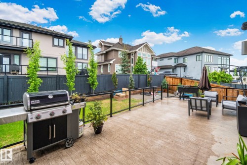 Spacious outdoor deck featuring wood-finish flooring, glass panel railing, and a dark privacy fence - 4509 Wingfield Bay Bay, Edmonton, AB 