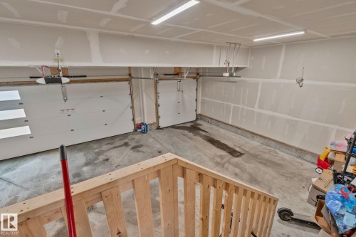 Two overhead garage doors with automatic openers, concrete flooring, and fluorescent lighting - 4509 Wingfield Bay Bay, Edmonton, AB 
