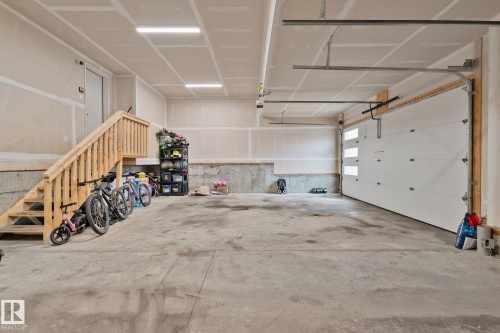 Spacious garage featuring a concrete floor, bright overhead lighting, and a contemporary garage door with frosted glass panels - 4509 Wingfield Bay Bay, Edmonton, AB 