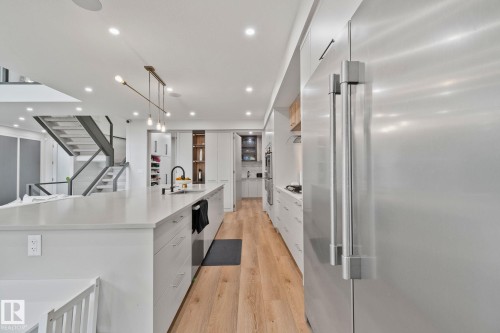 Gourmet kitchen with a large central island featuring a matte black gooseneck faucet and a linear pendant light fixture - 4509 Wingfield Bay Bay, Edmonton, AB 