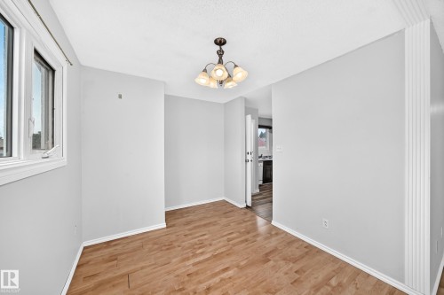 Open concept area featuring wood-finish flooring, white trim, and a multi-light chandelier - 1103 56 Street, Edmonton, AB 