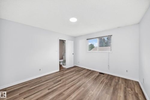 Spacious room featuring wood-finish flooring, light grey walls, and white trim - 1103 56 Street, Edmonton, AB 