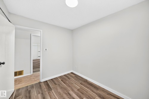 Room with wood-finish flooring, white baseboards, and light gray walls - 1103 56 Street, Edmonton, AB 