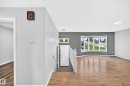 Inviting entryway featuring a white door with transom window, complemented by a white handrail and light wood-finish flooring - 1103 56 Street, Edmonton, AB 