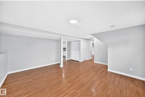 Open-concept living area with wood-finish flooring, recessed lighting, and light gray wall tones - 1103 56 Street, Edmonton, AB 