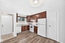 Kitchen featuring wood-finish flooring, wood cabinetry, white appliances, and a tiled backsplash - 1103 56 Street, Edmonton, AB 