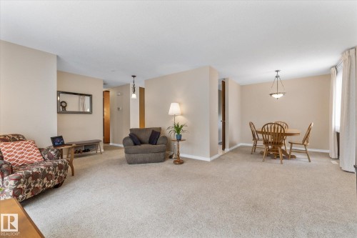 Carpeted living and dining areas with neutral wall tones and white baseboards - 15112 76A Avenue, Edmonton, AB 