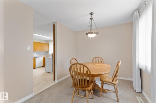 Dining area featuring a suspended ceiling light fixture, carpeted flooring, and a large window with sheers - 15112 76A Avenue, Edmonton, AB 