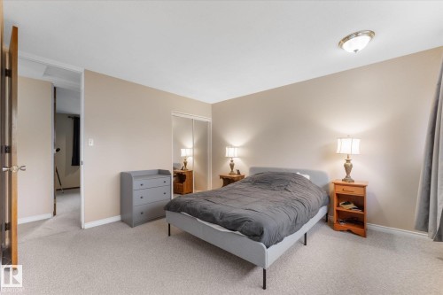 Bedroom featuring light-colored carpet, neutral wall paint, and a ceiling-mounted light fixture - 15112 76A Avenue, Edmonton, AB 