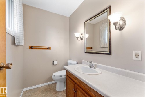 Bathroom featuring a wood-finish vanity with a white countertop and integrated sink - 15112 76A Avenue, Edmonton, AB 