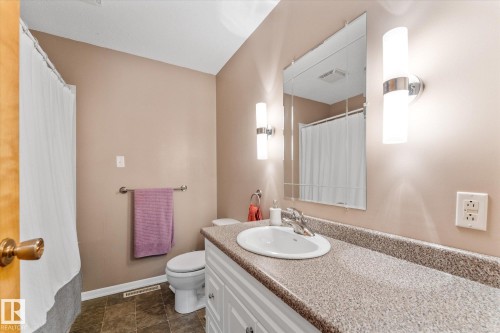 Bathroom featuring a white vanity with an integrated sink, a speckled countertop, and a mirrored medicine cabinet - 15112 76A Avenue, Edmonton, AB 